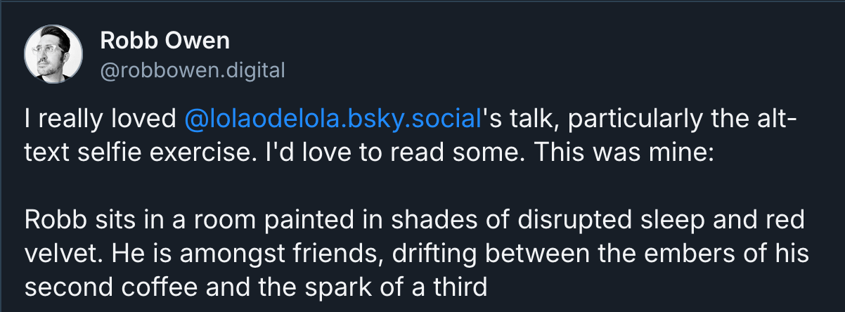 Robb's (@robbowen.digital on Bluesky) alt text selfie which reads "Robb sits in a room painted in shades of disrupted sleep and red velvet. He is amongst friends, drifting between the embers of his second coffee and the spark of a third"