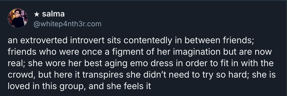Salma's (@whitep4nth3r.com on Bluesky) alt text selfie which reads "an extroverted introvert sits contentedly in between friends; friends who were once a figment of her imagination but are now real; she wore her best aging emo dress in order to fit in with the crowd, but here it transpires she didn’t need to try so hard; she is loved in this group, and she feels it"